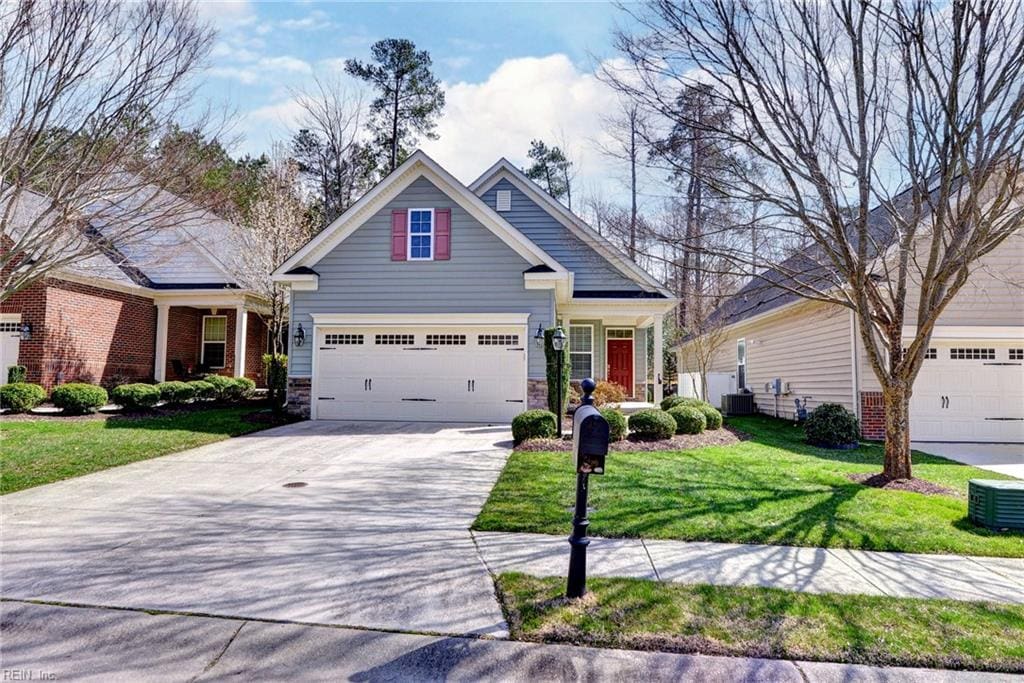 craftsman-style house with stone siding, central AC unit, concrete driveway, and a front lawn
