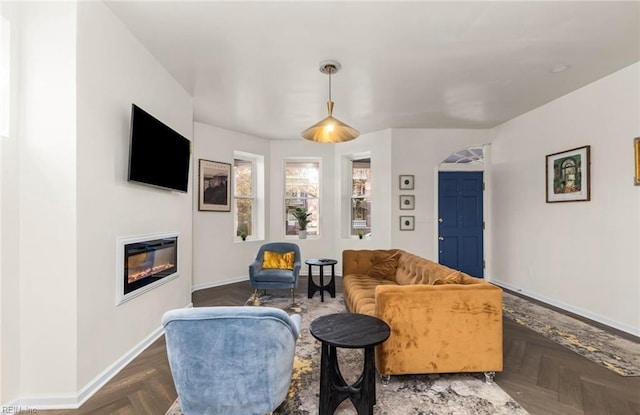 living area with baseboards and a glass covered fireplace