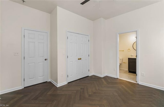unfurnished bedroom with baseboards, a closet, ceiling fan, and ensuite bathroom