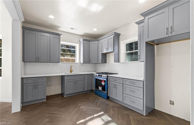 kitchen featuring gray cabinets, visible vents, stainless steel gas stove, and a sink
