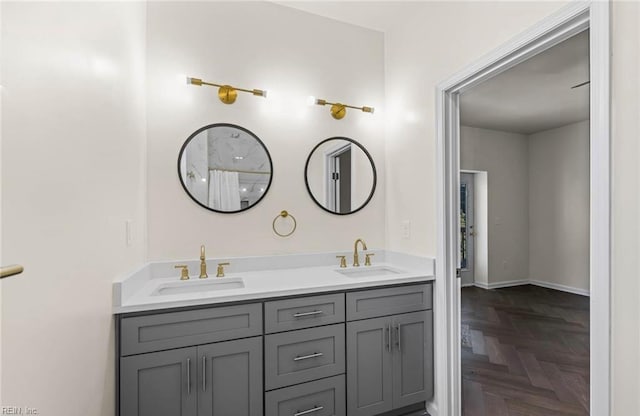 bathroom featuring baseboards, double vanity, and a sink