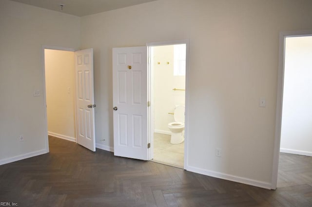 unfurnished bedroom with ensuite bathroom and baseboards