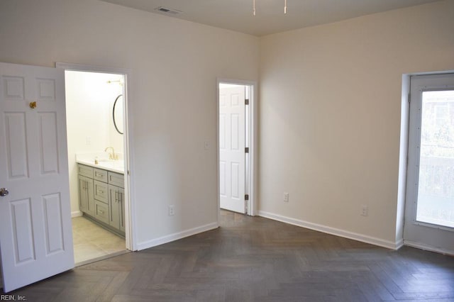 unfurnished bedroom featuring a sink, baseboards, multiple windows, and visible vents