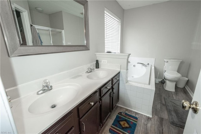 full bath with a garden tub, double vanity, a sink, and wood finished floors