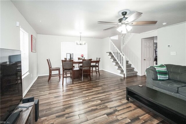living area with baseboards, stairway, dark wood finished floors, and ceiling fan with notable chandelier