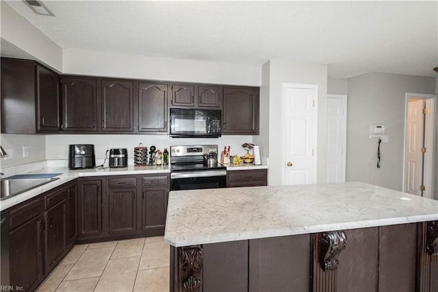kitchen with stainless steel electric range, black microwave, light tile patterned floors, a kitchen island, and dark brown cabinets
