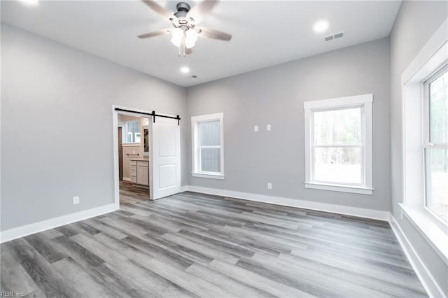 11AC Glass Rd, Hayes, VA 23072 - unfurnished bedroom with visible vents, wood finished floors, a barn door, baseboards, and ceiling fan
