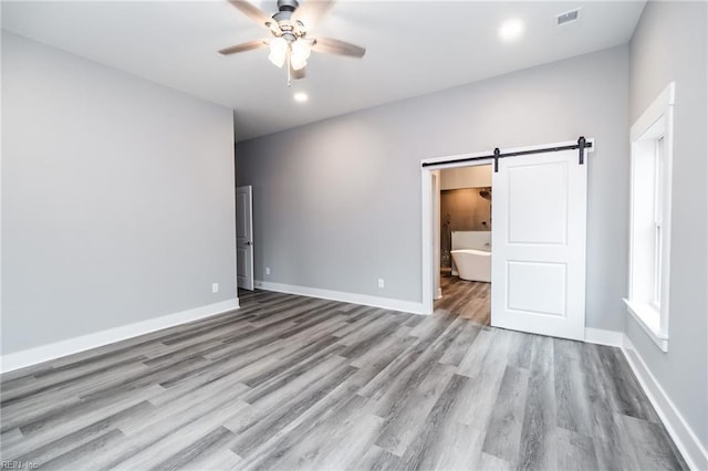 11AC Glass Rd, Hayes, VA 23072 - unfurnished bedroom featuring wood finished floors, visible vents, baseboards, ceiling fan, and a barn door