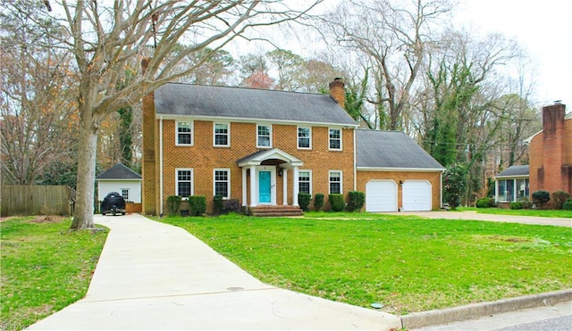 colonial home featuring a chimney, an attached garage, brick siding, a front lawn, and driveway