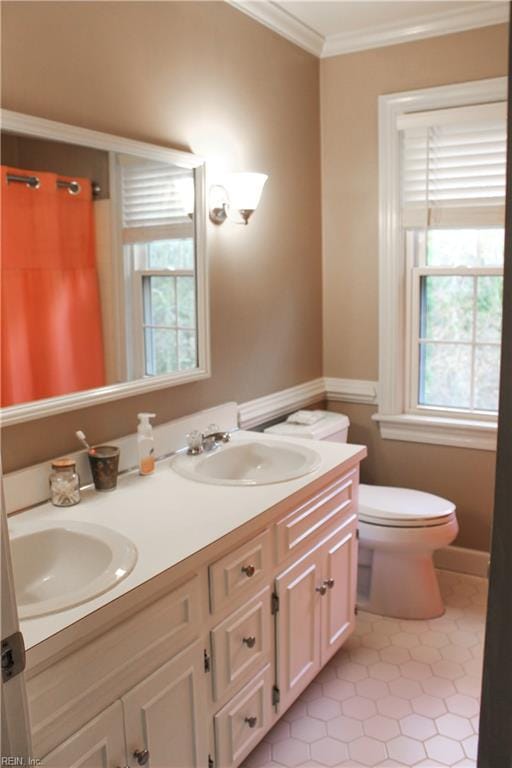 full bath featuring double vanity, a sink, toilet, and crown molding