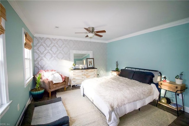 bedroom featuring baseboards, wallpapered walls, crown molding, and wood finished floors