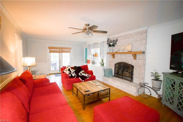 living area featuring a fireplace, wood finished floors, ornamental molding, and a ceiling fan