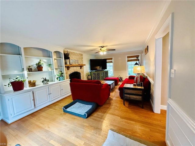 living room with ornamental molding, light wood-style floors, and a fireplace