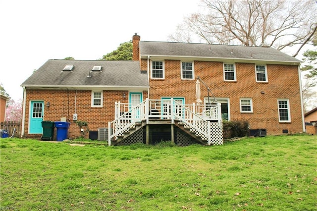 rear view of property with stairway, a chimney, a deck, brick siding, and a lawn