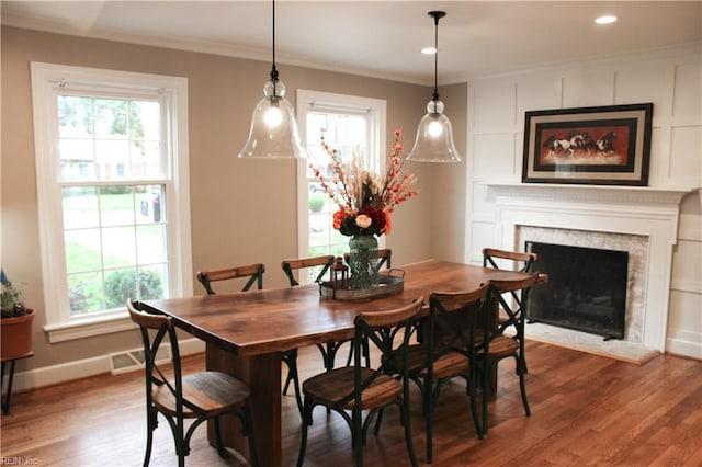 dining area featuring baseboards, a fireplace, wood finished floors, and ornamental molding