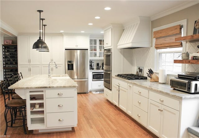 kitchen with white cabinetry, open shelves, custom range hood, stainless steel appliances, and a sink