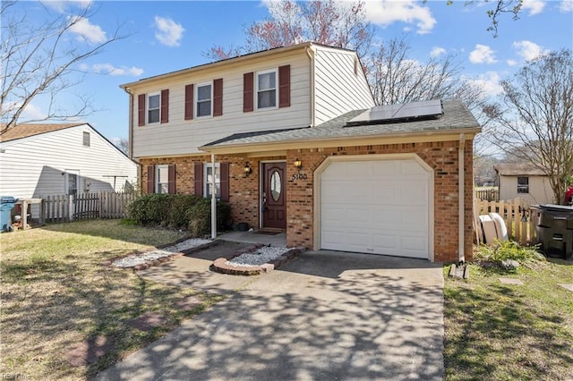 colonial house with fence, roof mounted solar panels, an attached garage, brick siding, and driveway