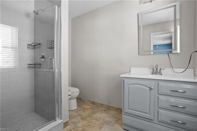 full bathroom with stone finish floor, baseboards, toilet, vanity, and a stall shower