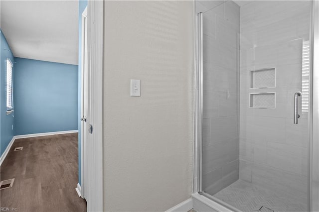 bathroom featuring a stall shower, baseboards, visible vents, and wood finished floors