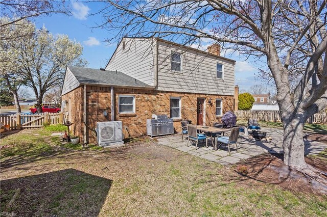 rear view of property featuring a chimney, fence, ac unit, brick siding, and a patio area