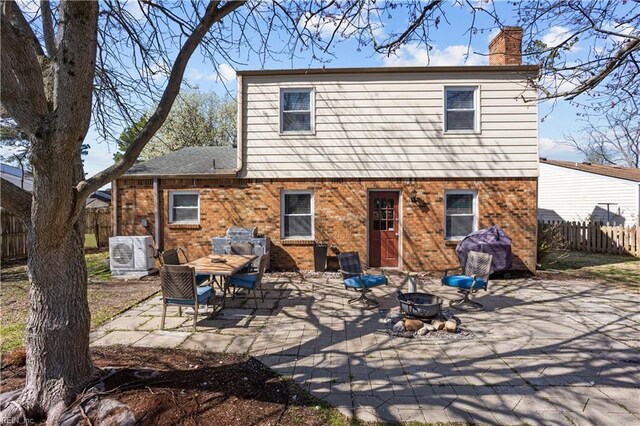 rear view of house featuring brick siding, an outdoor fire pit, fence, and a patio area