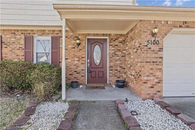 property entrance with an attached garage and brick siding