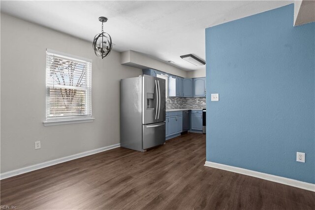 kitchen with stainless steel fridge, baseboards, dark wood finished floors, tasteful backsplash, and an inviting chandelier