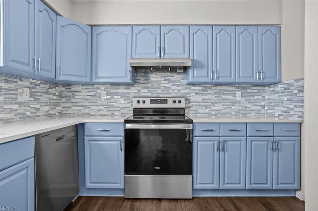 kitchen with under cabinet range hood, blue cabinets, dark wood finished floors, and appliances with stainless steel finishes