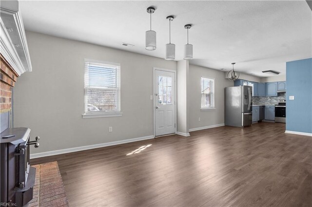 unfurnished living room with dark wood-style floors, visible vents, baseboards, and a wealth of natural light