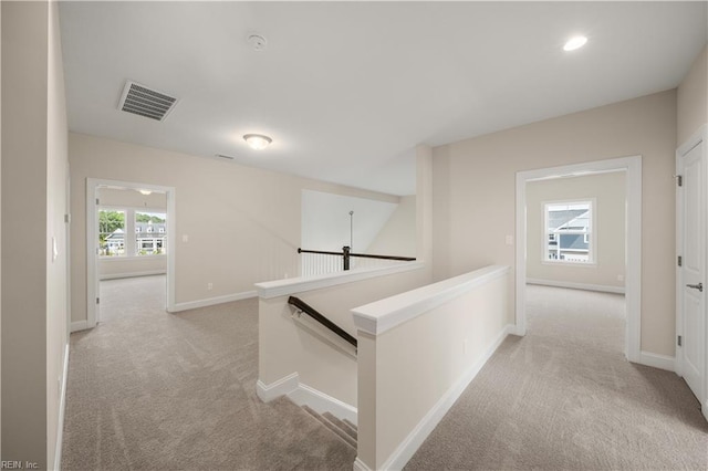hall with an upstairs landing, light carpet, baseboards, visible vents, and recessed lighting