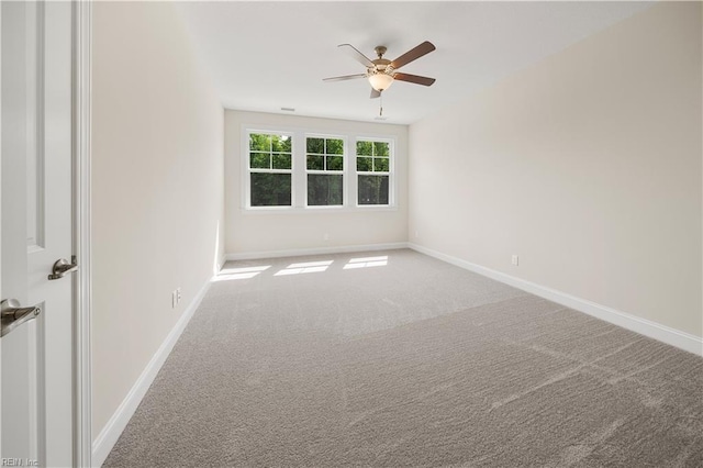 spare room featuring a ceiling fan, carpet, and baseboards