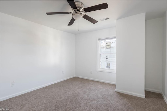 empty room with baseboards, visible vents, carpet flooring, and a ceiling fan