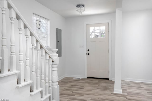 entryway featuring electric panel, baseboards, stairs, and wood finished floors