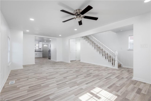 unfurnished living room with light wood finished floors, baseboards, ceiling fan, recessed lighting, and stairway