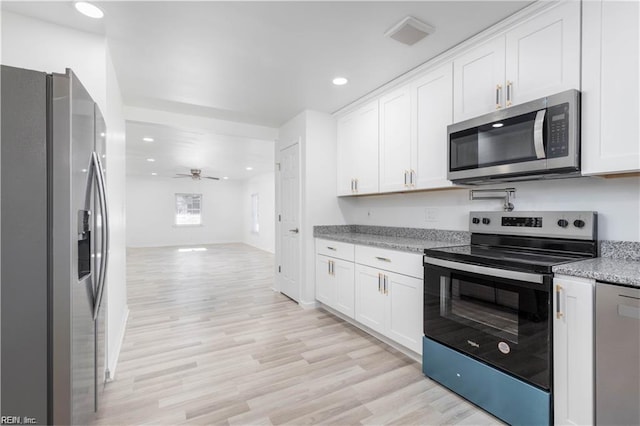 kitchen with open floor plan, white cabinetry, appliances with stainless steel finishes, and light wood-style floors