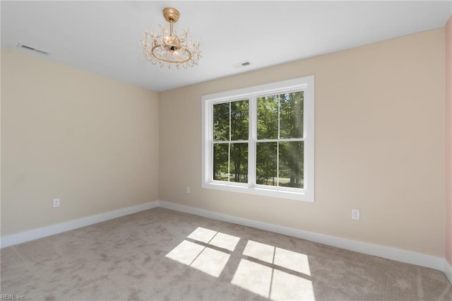 spare room with baseboards, visible vents, an inviting chandelier, and carpet