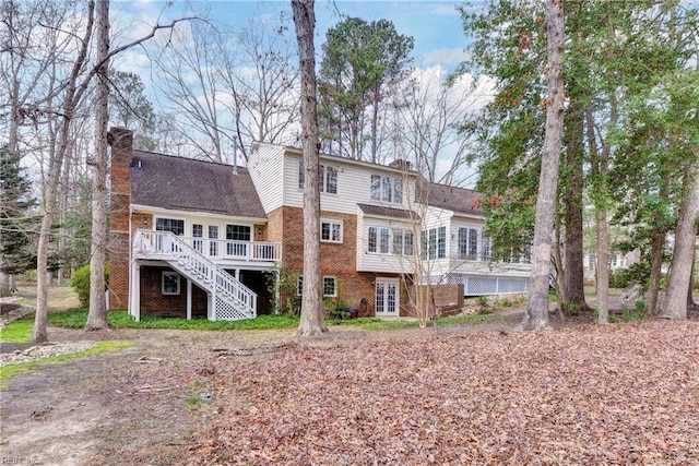 rear view of property with brick siding, stairs, and a chimney