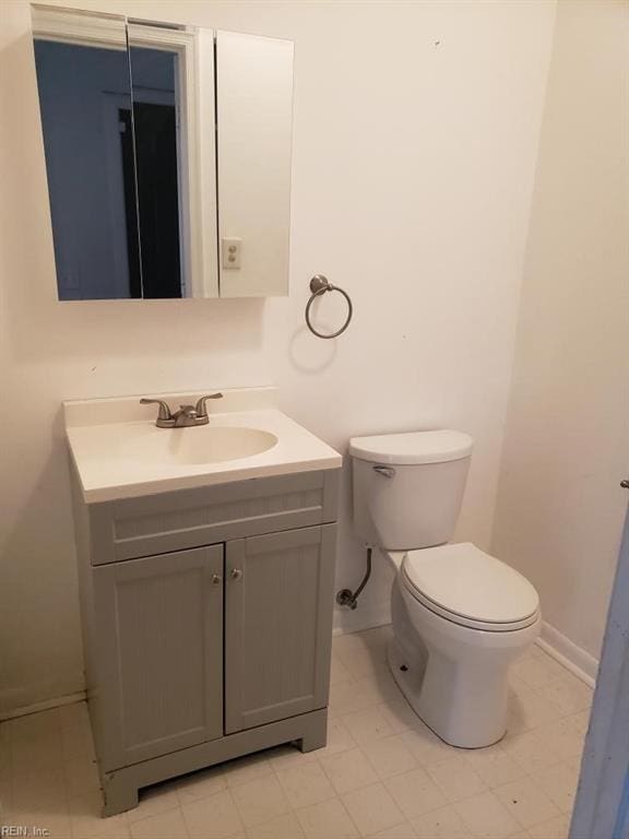 bathroom with toilet, vanity, and baseboards