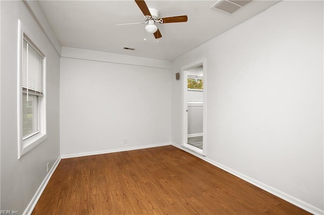 empty room featuring baseboards, visible vents, a ceiling fan, and wood finished floors