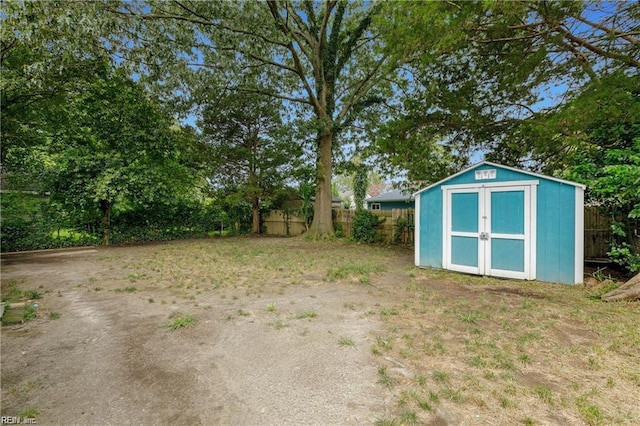 view of yard with an outdoor structure, fence, and a storage shed