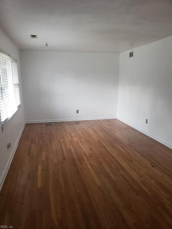 spare room featuring dark wood-type flooring, baseboards, and visible vents