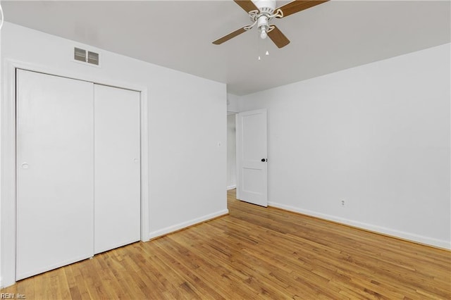 unfurnished bedroom with a closet, visible vents, baseboards, wood finished floors, and a ceiling fan