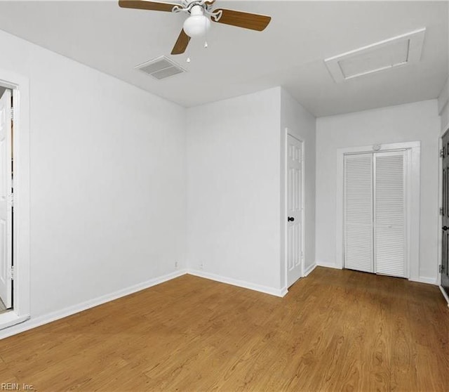unfurnished bedroom with attic access, baseboards, visible vents, and wood finished floors