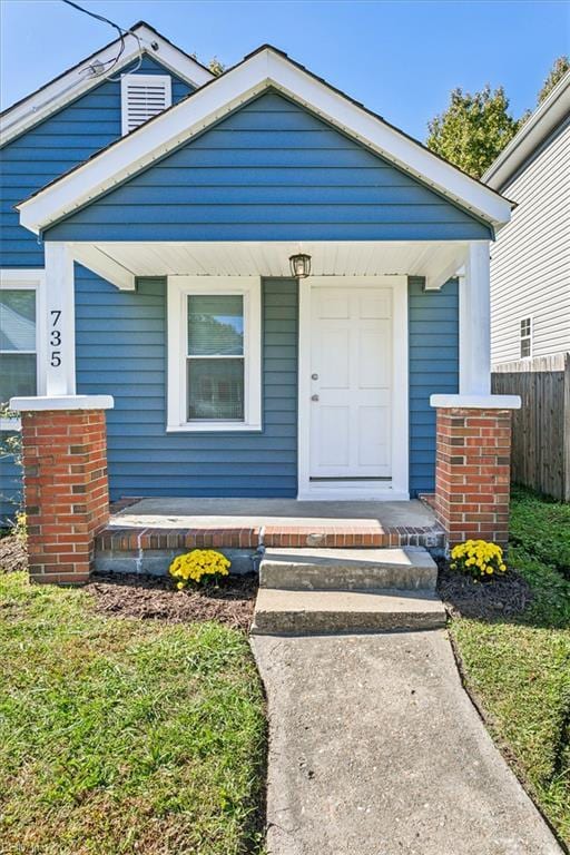 doorway to property with covered porch and fence