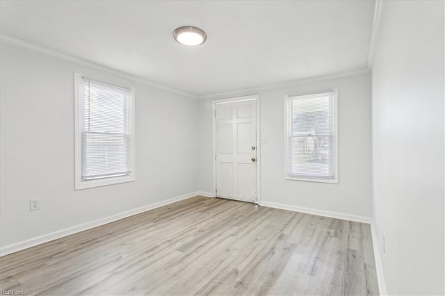 spare room with ornamental molding, baseboards, and light wood-type flooring