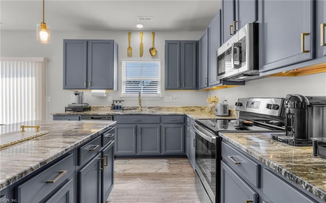 kitchen with visible vents, a sink, light stone counters, and appliances with stainless steel finishes