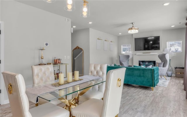 dining space featuring a glass covered fireplace, plenty of natural light, recessed lighting, and light wood finished floors