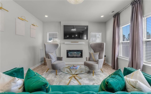 living room featuring wood finished floors, a glass covered fireplace, baseboards, and recessed lighting