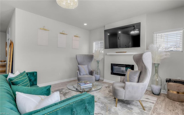 living area featuring baseboards, recessed lighting, wood finished floors, and a glass covered fireplace
