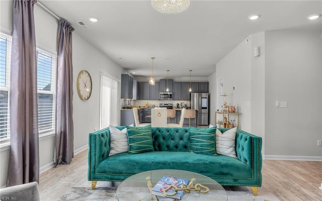 living room featuring baseboards, visible vents, light wood-style flooring, and recessed lighting